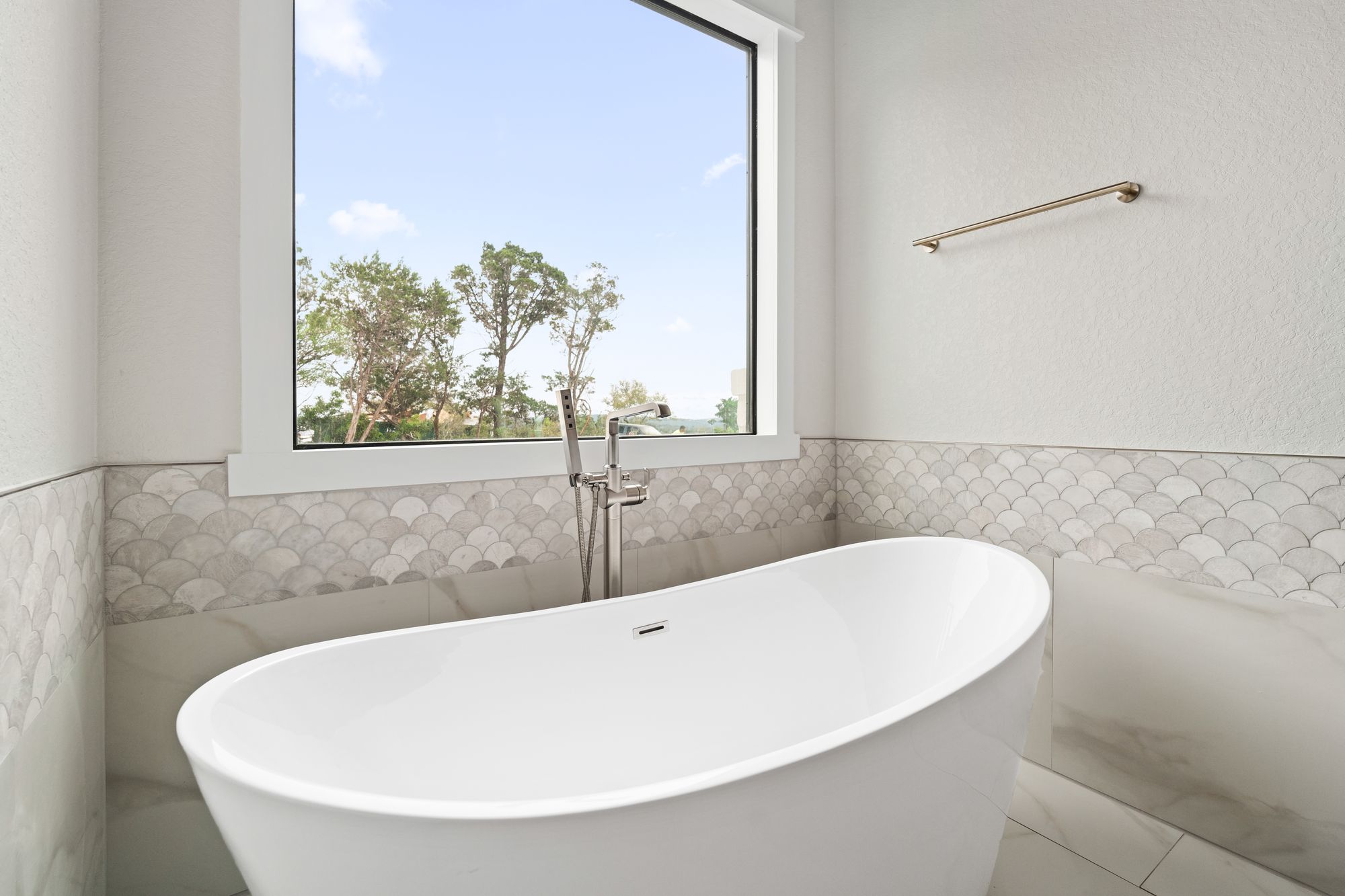 Freestanding tub framed by picture window